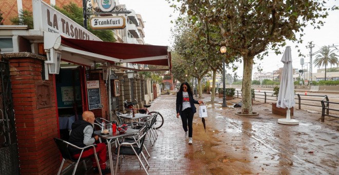 23/10/2019.- Una mujer camina junto a un bar por una calle cubierta de lodo después de las inundaciones causadas por lluvias torrenciales en Arenys de Mar. REUTERS / Albert Gea