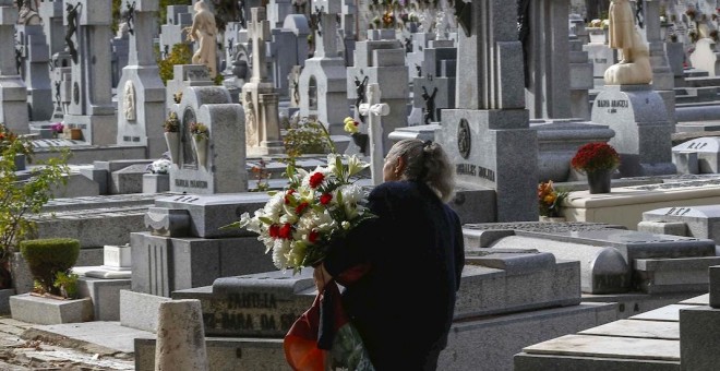 Una mujer con flores visita el madrileño cementerio de La Almudena, el Día de Difuntos. EFE/Paco Campos