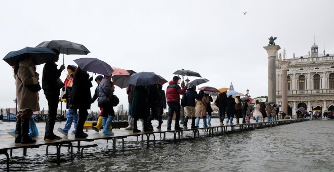 Decenas de transeúntes hacen cola en una pasarela durante este martes durante la temporada de marea alta. REUTERS