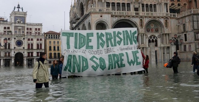 Varias personas sujetan una pancarta en la que se lee 'La  marea está subiendo y así estamos'. EFE/Andrea Merola
