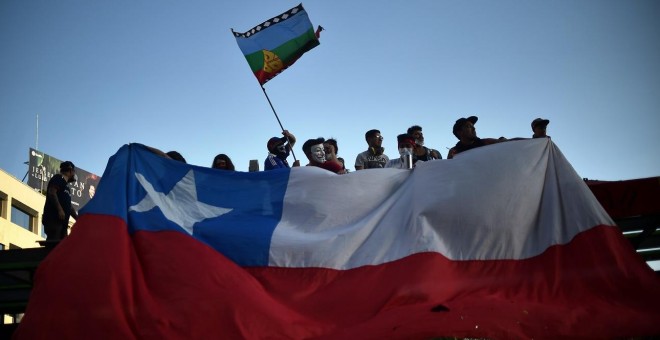 12/11/2019 - Manifestantes sostienen la bandera de Chile y la Mapuche. / AFP - RODRIGO ARANGUA