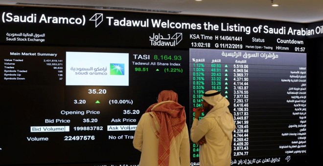 Dos personas observan el panel de la Bolsa de la Riad (Tadawul) los primeros movimientos de Saudi Aramco, tras el estreno bursátil de la petrolera estatal árabe. REUTERS/Ahmed Yosri