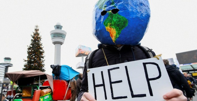 Un manifestante disfrazado de planeta Tierra sujeta un cartel en el que se puede leer 'ayuda'. REUTERS/Piroschka van de Wouw