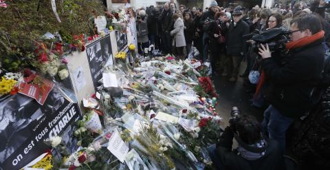 Ciudadanos dejan flores y mensajes junto al edificio de la publicación satírica 'Charlie Ebdo en París. /REUTERS