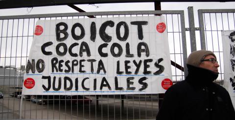 Un empleado de Coca-Cola junto a una pancarta que pide que la empresa acate la sentencia judicial. -JAIRO VARGAS