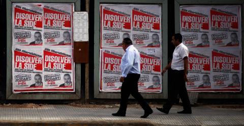 Dos hombres caminan al lado de unos carteles de AMIA sobre Nisman, en Buenos AIres. REUTERS/Marcos Brindicci