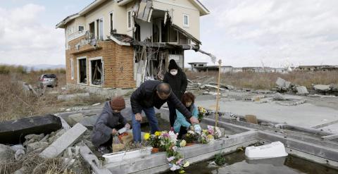 Una familia coloca flores y ora por sus parientes víctimas del terremoto y el tsunami del 11 de marzo de 2011 en el país. EFE/KIMIMASA MAYAMA