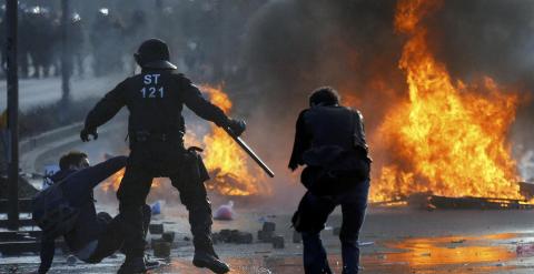 Un policía a punto de golpear con su porra a un manifestante en Fráncfort. /REUTERS