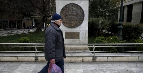 Un hombre pasa junto a una réplica de un dracma, la monedz griega antes del euro, junto al Ayuntamiento de Atenas.. REUTERS/Alkis Konstantinidis
