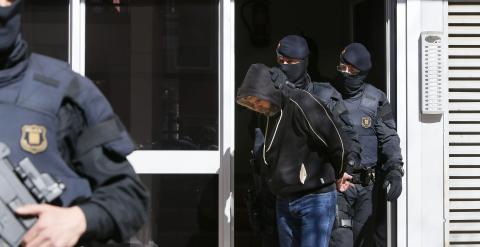 Agentes de los Mossos d'Esquadra custodian a una de las nueve personas que han sido detenidas en el marco de una operación contra el terrorismo yihadista que están llevando a cabo la policía catalana, coordinada por el juzgado número 1 de la Audiencia Nac