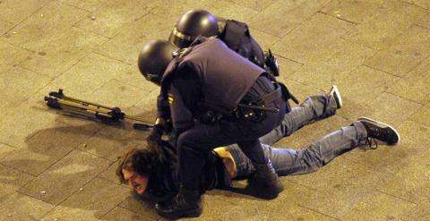 Dos antidisturbios inmovilizan en el suelo a un periodista, el día 14 de mayo de 2012, durante el desalojo de Sol en el primer aniversario del movimiento.- EFE