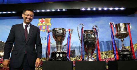 El presidente del FC Barcelona, Josep María Bartomeu, posa con los trofeos de la Liga, Liga de Campeones y Copa del Rey al finalizar su comparecencia. /EFE