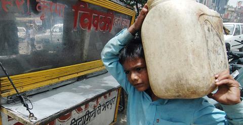 Sachin, de nueve años, carga con un recipiente con agua para el puesto de comida en el que trabaja Amritsar. AFP/Narinder NANU
