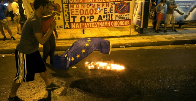 An anti-austerity demonstrator throws a European Union flag into a fire in front of the parliament in Athens, Greece July 22, 2015. Greek Prime Minister Alexis Tsipras sought on Wednesday to contain a rebellion in his left-wing Syriza party ahead of a vot