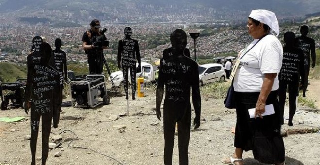 La familiar de uno de los desaparecidos de la Comuna 13, en Medellín, camina entre siluetas que representan a las víctimas enterradas en el lugar.