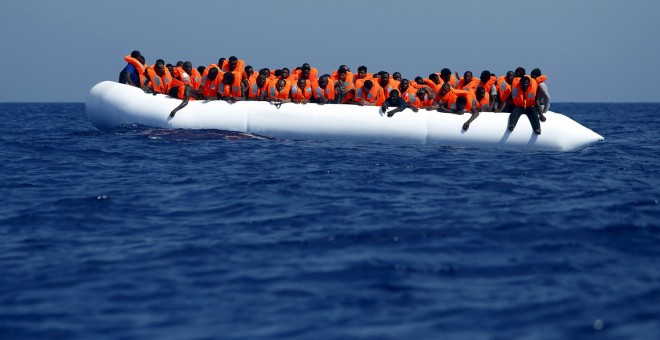 Inmigrantes en la embarcación de goma en la que han atravesado el Mediterráneo esperan a ser rescatados frente a la costa de Libia. REUTERS/Darrin Zammit Lupi