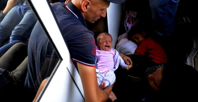 Un emigrante de Alepo, Siria, con su bebé de 30 días de edad en un tren que pasa por Macedonia. Tras ir a pie hasta la frontera de Macedonia, decenas de miles de emigrantes se suben al tren en la estación de Gevgelia para viajar 200km hacia el norte. REU