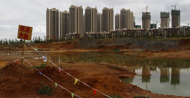 Un letrero que dice 'Estanque, peligro', junto a las obras de unas edificaciones residenciales en Chenggong, en la provincia china de Yunnan. REUTERS / Wong Campion