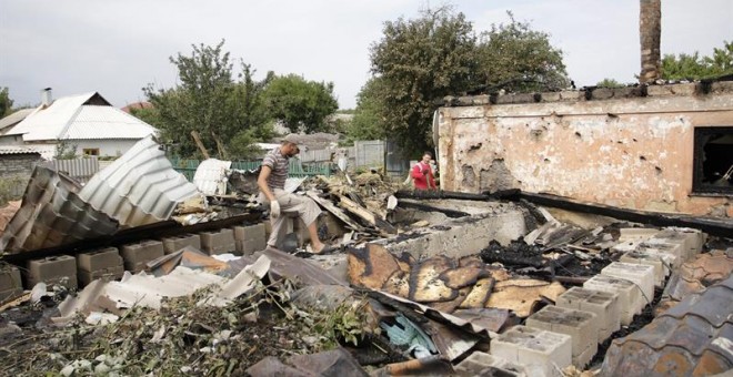 Varios lugareños revisan los restos de un edificio tras un bombardeo en la ciudad de Donetsk (Ucrania) este 17 de agosto de 2015. Al menos dos soldados ucranianos murieron y y otros siete resultaron heridos en las últimas 24 horas en acciones de combate e