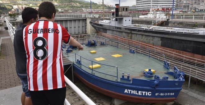 Dos jóvenes observan la legendaria gabarra con la que el Athletic Club celebró sus títulos en 1983 y 1984. EFE/ Miguel Toña