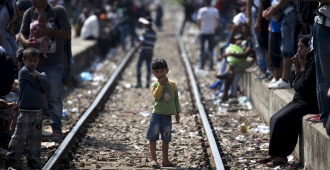 Un niño sirio, que huye de la guerra en su país, espera en sobre las vías al tren que les llevará desde Macedonia hasta Servia.- REUTERS/Stoyan Nenov