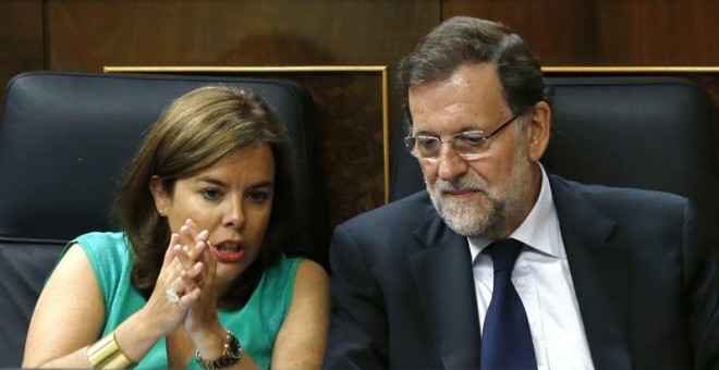 El presidente del Gobierno, Mariano Rajoy (d), y la vicepresidenta, Soraya Sáenz de Santamaría (i), conversan durante el segundo día del debate de totalidad del proyecto de Ley de Presupuestos para 2016, en el pleno del Congreso. EFE/Sergio Barrenechea