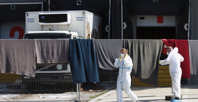 Miembros del equipo forense caminan frente al camión donde fueron encontrados los cadáveres de 70 refugiados, en la la localidad de  Nickelsdorf, Austria.