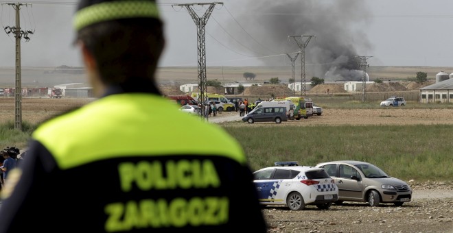 Un policía de Zaragoza y al fondo el humo que queda tras las explosiones en la empresa de pirotecnia./REUTERS/Luis Correas