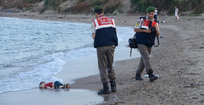 Dos agentes de la gendarmería turca, junto al cadaver de un niño que formaba parte del grupo de refugiados sirios que naufragaron intentando llegar a la isla de Kos. REUTERS/Nilufer Demir