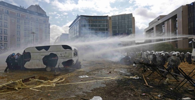 Ganaderos protestando contra la crisis del sector lácteo en Bruselas, mientras la Policía usaba cañones de agua para disuadirles. REUTERS