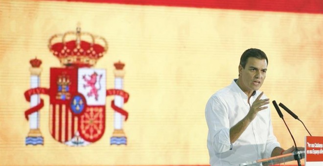 Pedro Sánchez con la bandera rojigualda durante el acto. EFE/Andreu Dalmau