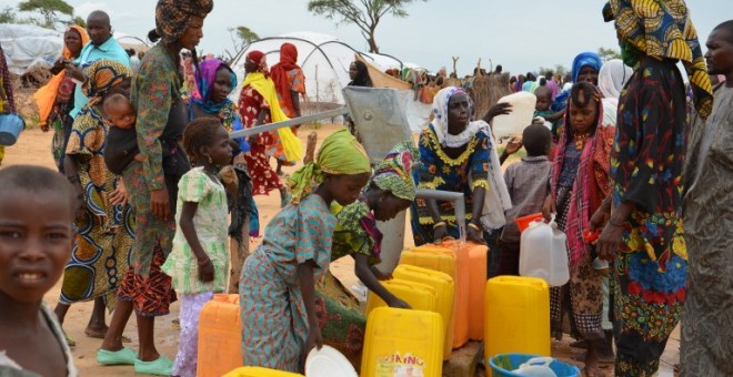 Una mujer reparte agua en un campo de refugiados que han tenido que huir por la violencia de Boko Haram. - AFP