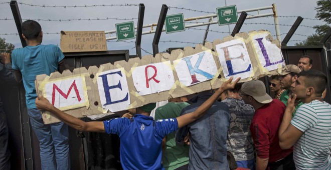 Varios inmigrantes llevan un cartel en el que se puede leer 'Merkel', en honor a la cancillera alemana, en la frontera con Hungría cerca del pueblo de Horgos./ REUTERS/ Marko Djurica