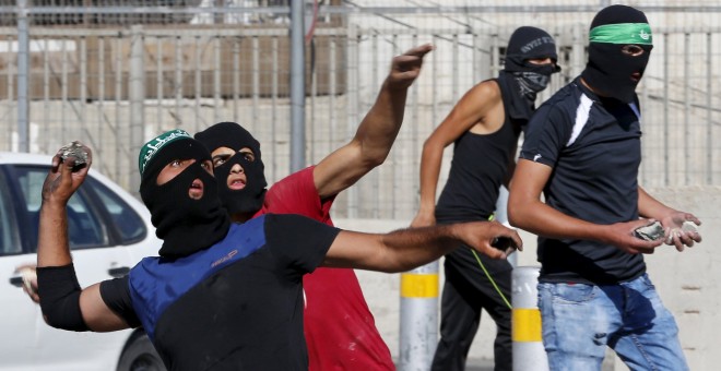 Los palestinos lanzan piedras hacia la policía fronteriza israelí durante los enfrentamientos en un puesto de control entre el campamento de refugiados de Shuafat y Jerusalén./ REUTERS/ Ammar Awad