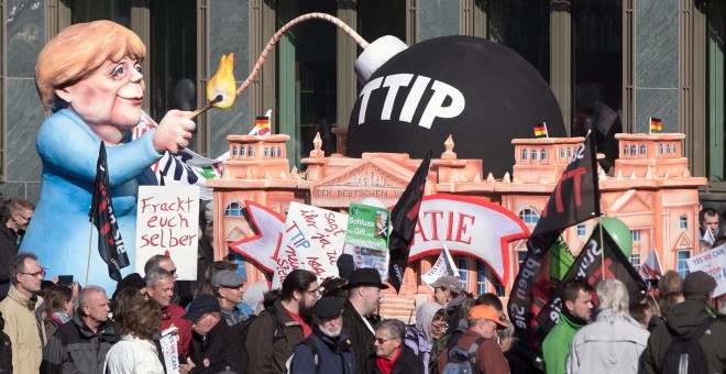 Un muñeco que representa a la canciller alemana, Angela Merkel, encendiendo 'la bomba TTIP', en la manifestación de Berlín contra el acuerdo comercial que negocia la UE con EEUU. EFE / EPA / JOERG CARSTENSEN