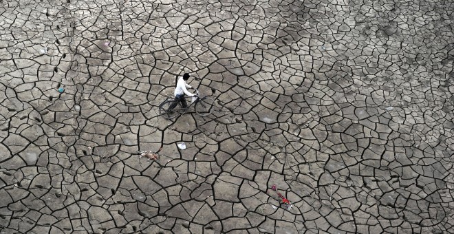 Un pescador indio empuja su bici por el barro seco a las orillas del río Yamuna, en Allahabad, India.  SANJAY KANOJIA (AFP)