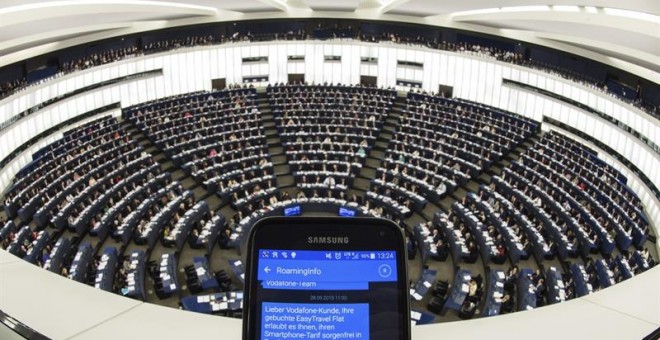 Una persona muestra un SMS con información de 'roaming' en su teléfono móvil durante el pleno del Parlamento Europeo en Estrasburgo (Francia) hoy, 27 de octubre de 2015. Los europarlamentarios votan la abolición de los recargos por el uso del teléfono móv