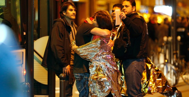 Supervivientes se abrazan antes de ser evacuados en autobús, cerca de la sala de conciertos Bataclan en París, donde los terroristas han matado a más de 100 rehenes.-  AFP PHOTO / FRANCOIS GUILLOT