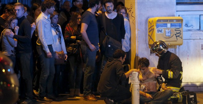 Un joven es atendido por dos bomberos cerca de la sala Bataclan en la noche del 13-N. /REUTERS