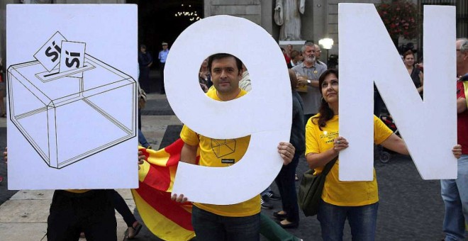 En la imagen, varias personas sostienen unos carteles sobre la consulta del 9N. EFE Alberto Estévez