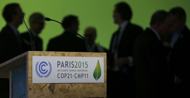 Varios participantes en la cumbre del clima dialogan tras el atril. REUTERS/Stephane Mahe