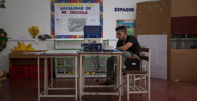 Un miembro de mesa electoral trabaja en una máquina de votación durante los preparativos para las elecciones. EFE/MIGUEL GUTIERREZ