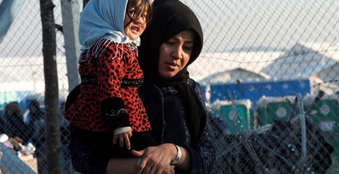 Una mujer carga a su bebé mientras se dirige al centro de registro de migrantes tras cruzar la frontera entre Macedonia y Grecua, en Macedonia. EFE