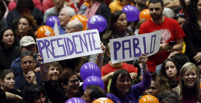 Unos asistentes al mitin de cierre de campaña de Podemos en el Pabellón de la Fuente de San Luis de Valencia sostienen unos carteles que dicen 'Presidente Pablo'. EFE/Kai Försterling