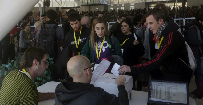 Vista a través de un cristal de los participantes en la votación realizada durante la asamblea de la CUP sobre la investidura de Artur Mas. EFE/Alberto Estévez
