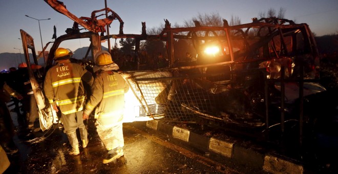 Varios bomberos inspeccionan los restos del autobús atacado. - REUTERS