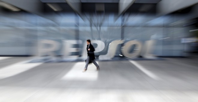 Un hombre pasa por delante del logo de Repsol en su sede de Madrid. REUTERS/Susana Vera