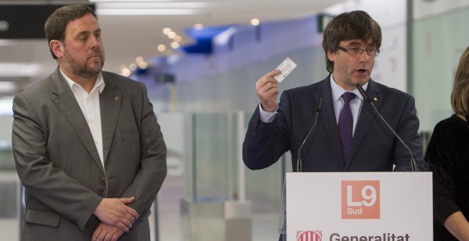 El president de la Generalitat, Carles Puigdemont, acompañado del vicepresidente del Gobierno catalán, Oriol Junqueras, muestra un billete de transporte público, durante el acto de inauguración del nuevo tramo de la Linea 9 (L9) del metro, que conecta la