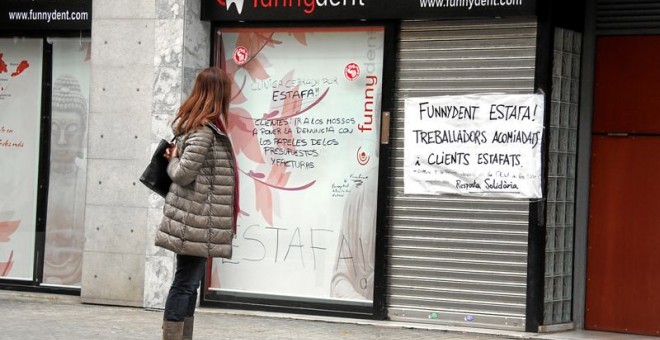 Una mujer lee la pancarta colocada en la puerta de la clínica Funnydent, en Mataró.- EFE