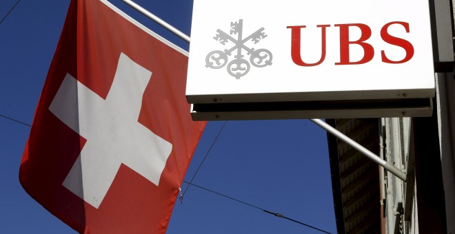 Foto de la bandera nacional de Suiza al lado del logotipo del banco suizo UBS en la ciudad de Riehen. REUTERS